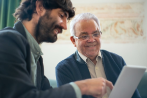 A senior looking at a laptop with a memory care staff member.