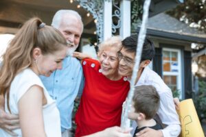 An elderly couple hugging their grandchildren