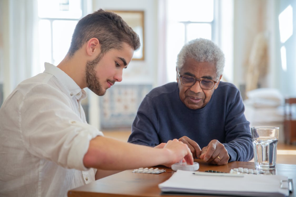 A caregiver helping a senior take their medicine.