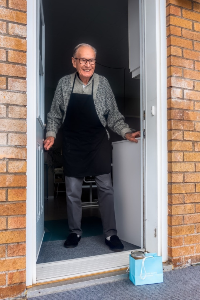 An old man standing and smiling.