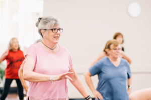 A senior in a pink shirt dancing