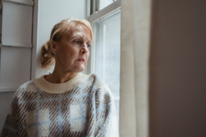 A senior staring out a window