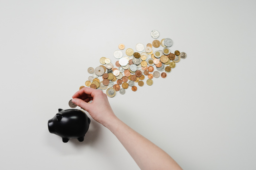 A person inserting a coin into a black piggy bank