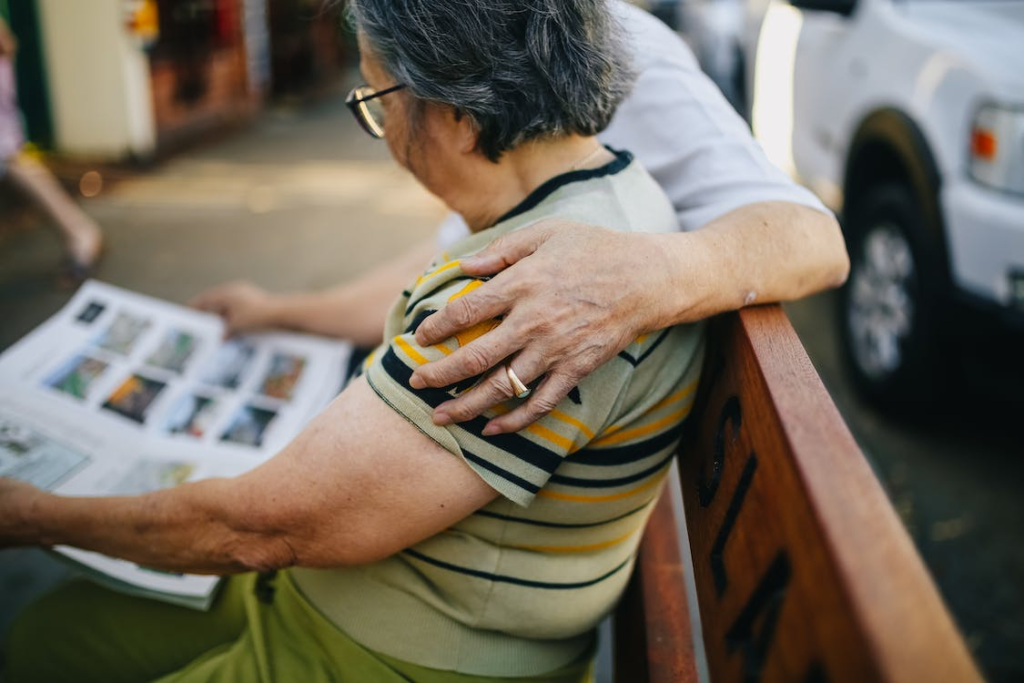 A person’s hand resting on a senior’s shoulder