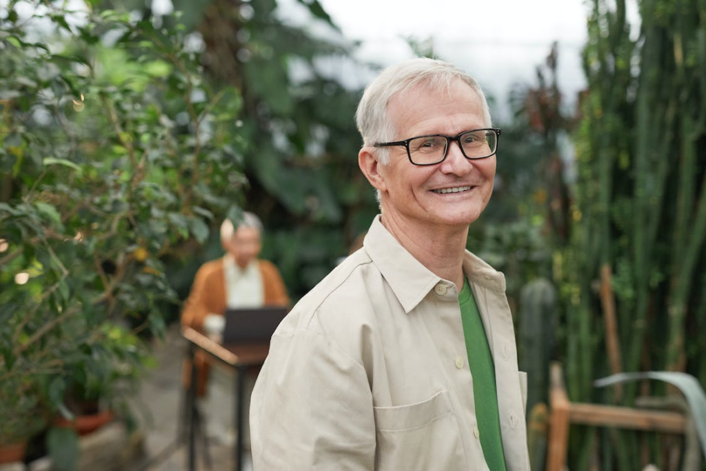  A senior smiling while surrounded by greenery