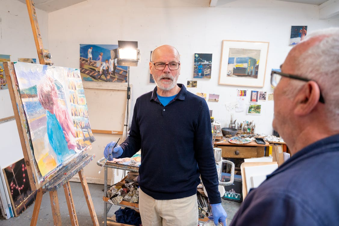 A senior standing next to an easel with a painting on it