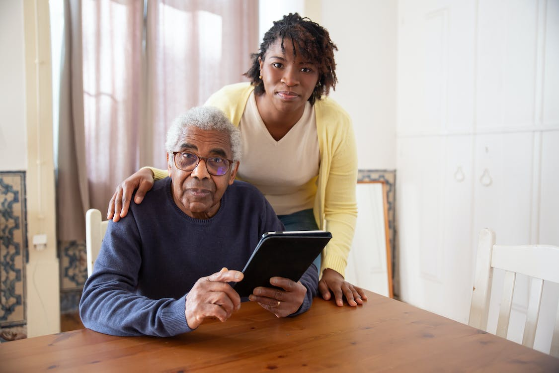 A senior and their caregiver smiling at the camera