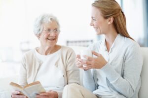 A senior reading a book with their caregiver next to them