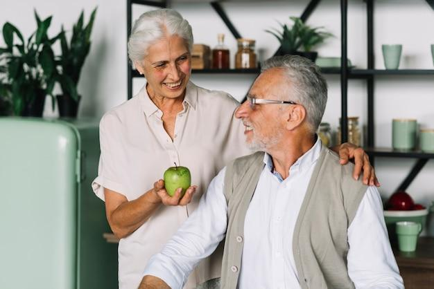 A senior offering her husband a green apple