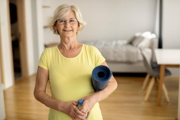 A senior holding a yoga mat