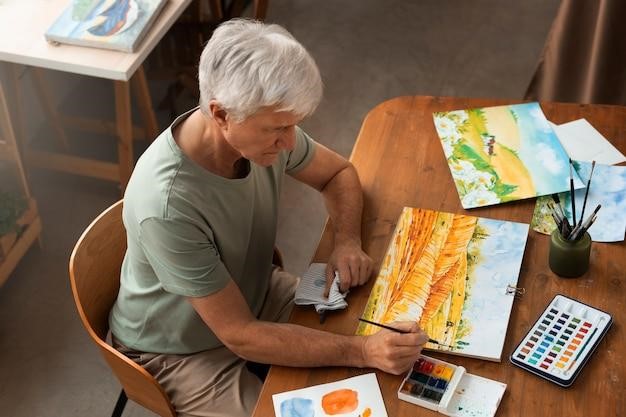 A senior painting a scenic landscape