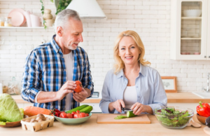 A senior couple cutting vegetables in a kitchen