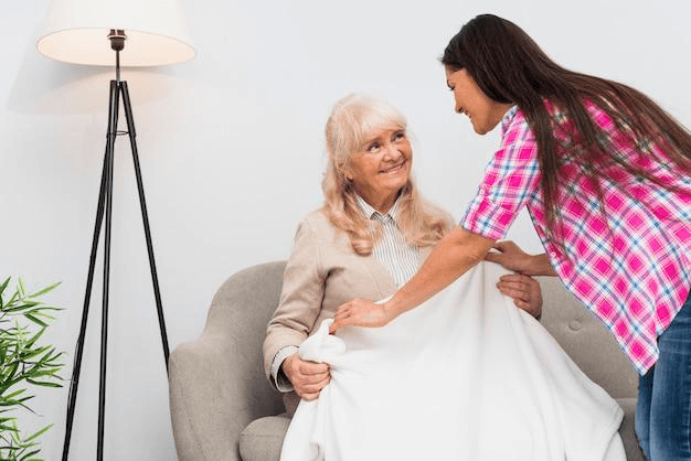 A caregiver giving a senior a blanket