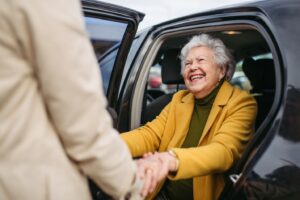 A senior stepping out of a car with their caregiver's support