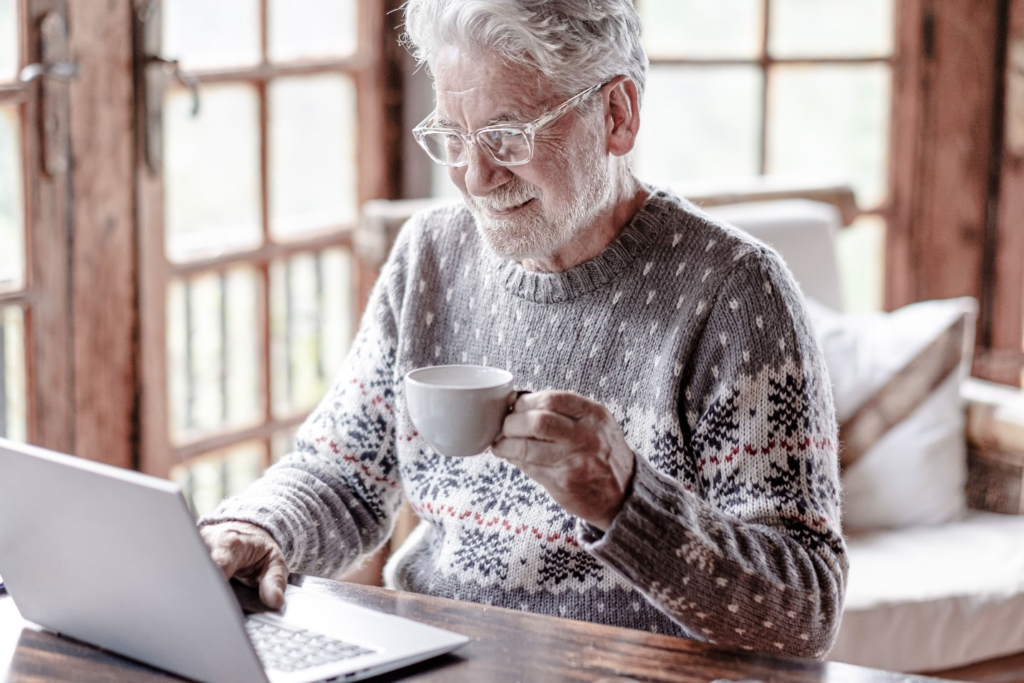 A senior having a warm beverage while wearing a cozy sweater