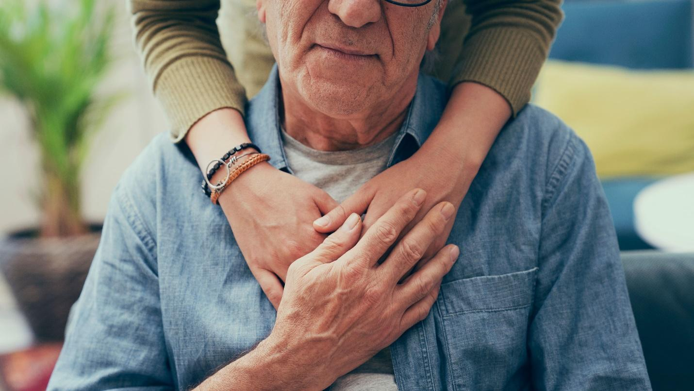 A senior placing a hand on a person’s arms around their shoulders